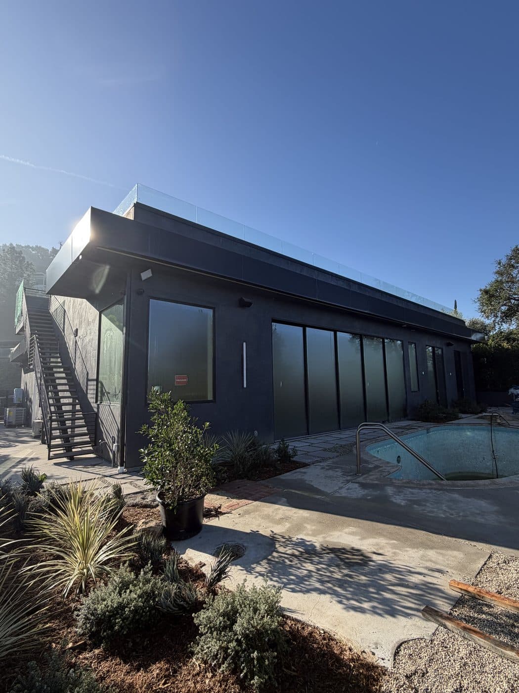 A modern pool house with a wall of clean sliding glass doors by Window Wizards