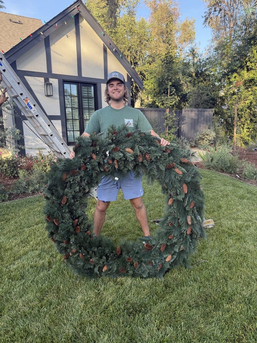 Window Wizards technician holding a large custom holiday wreath in a Los Angeles backyard