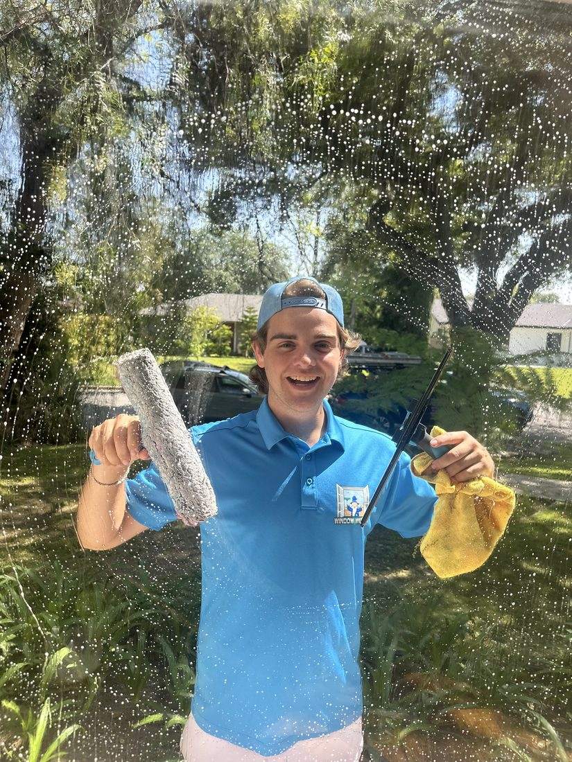 Smiling Window Wizards technician in a blue polo cleaning a Sierra Madre home's windows